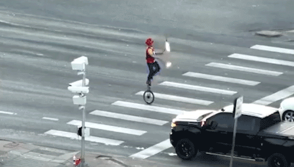 Fire-juggling unicyclist caught on camera blocking traffic in major roadway as police intervene
