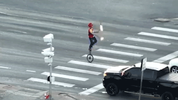 Fire-juggling unicyclist caught on camera blocking traffic in major roadway as police intervene